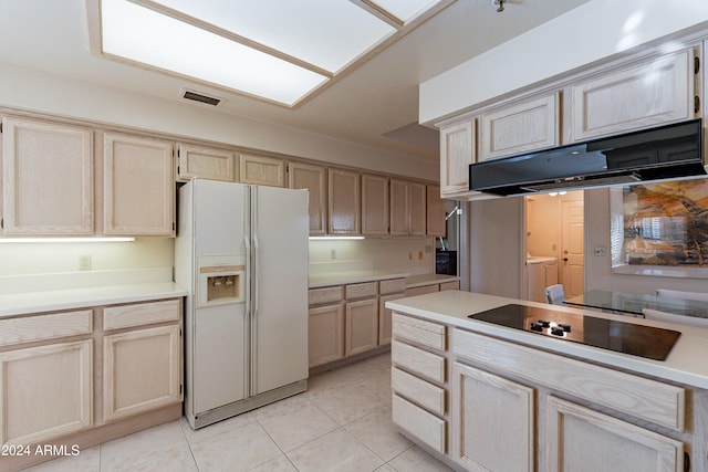 kitchen featuring light brown cabinets, white refrigerator with ice dispenser, independent washer and dryer, extractor fan, and black electric cooktop