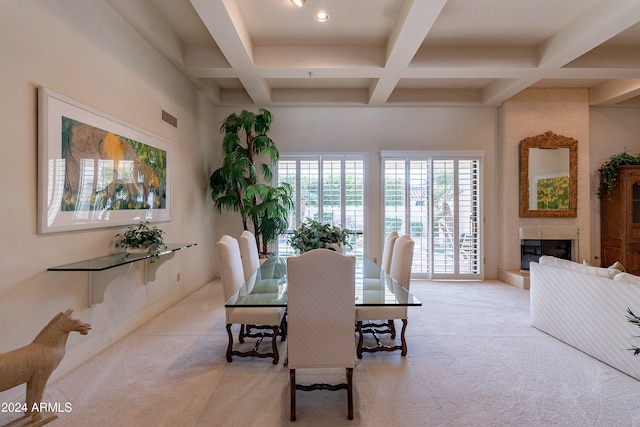 carpeted dining area with beamed ceiling, a large fireplace, and coffered ceiling