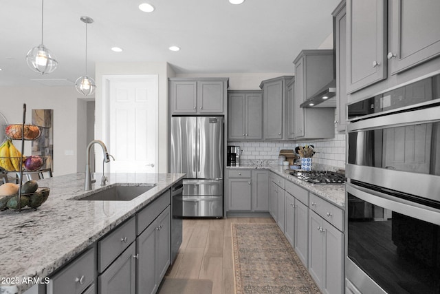 kitchen featuring stainless steel appliances, light hardwood / wood-style floors, sink, hanging light fixtures, and gray cabinetry