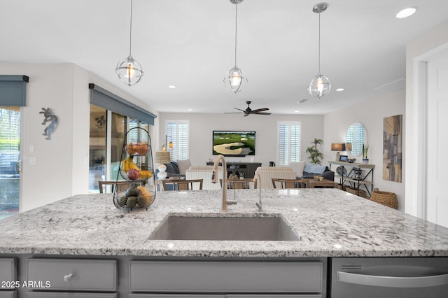 kitchen featuring light stone countertops, sink, hanging light fixtures, and an island with sink