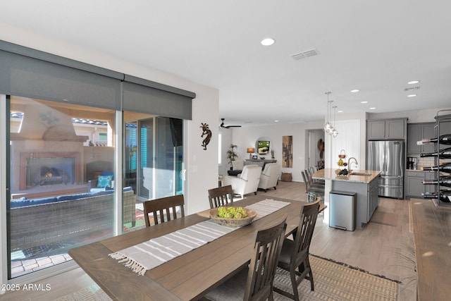 dining area featuring light wood-type flooring, ceiling fan, and sink