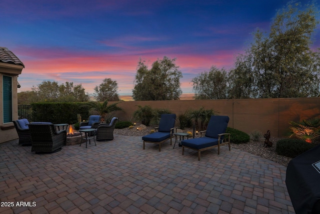 patio terrace at dusk with a fire pit and area for grilling