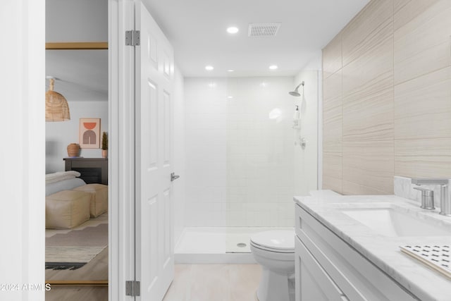 bathroom featuring vanity, toilet, and tiled shower