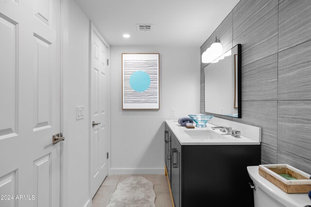 bathroom with tile patterned flooring, vanity, toilet, and tile walls