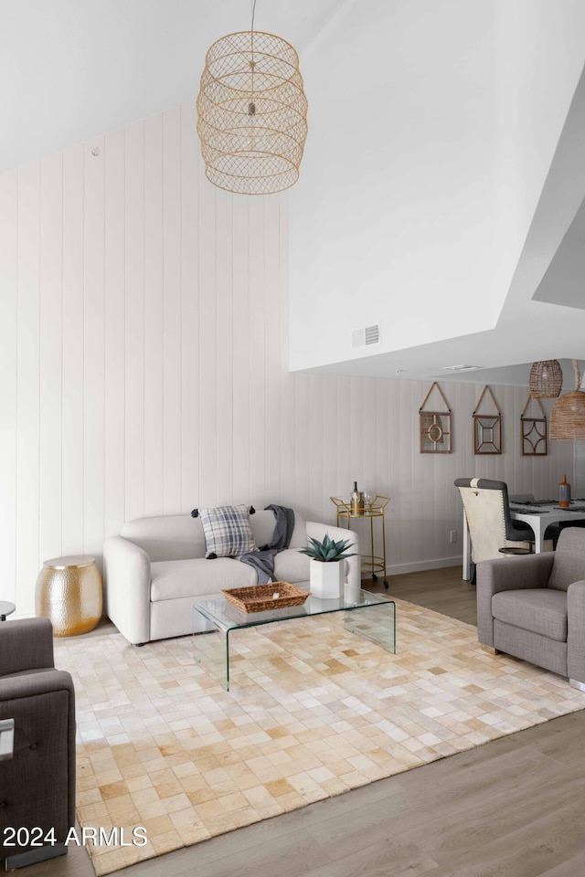 living room featuring wooden walls, a high ceiling, and light wood-type flooring