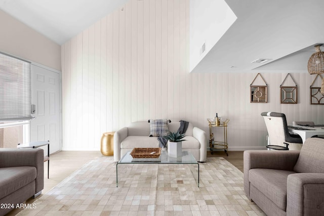 living room with wood walls, light hardwood / wood-style flooring, and vaulted ceiling