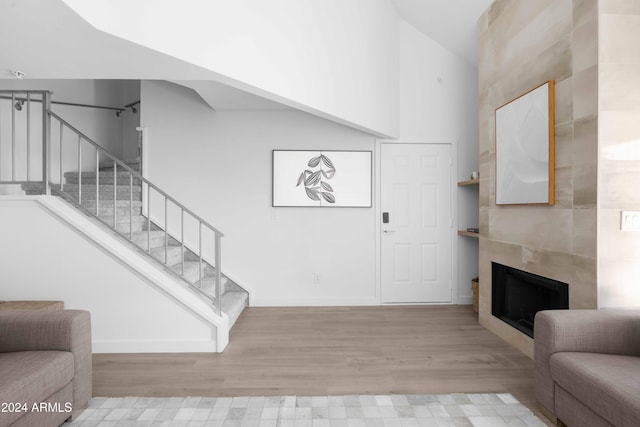 interior space featuring a tiled fireplace, a towering ceiling, and light hardwood / wood-style flooring