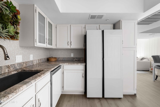 kitchen with backsplash, white cabinets, sink, light hardwood / wood-style flooring, and stainless steel dishwasher