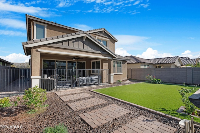 rear view of house featuring ceiling fan and a lawn