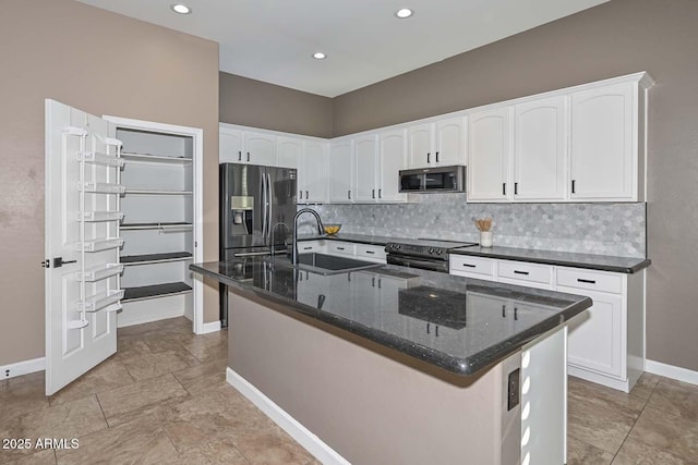 kitchen with sink, appliances with stainless steel finishes, a kitchen island with sink, decorative backsplash, and white cabinets