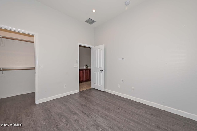 unfurnished bedroom with dark hardwood / wood-style floors, a closet, and a spacious closet