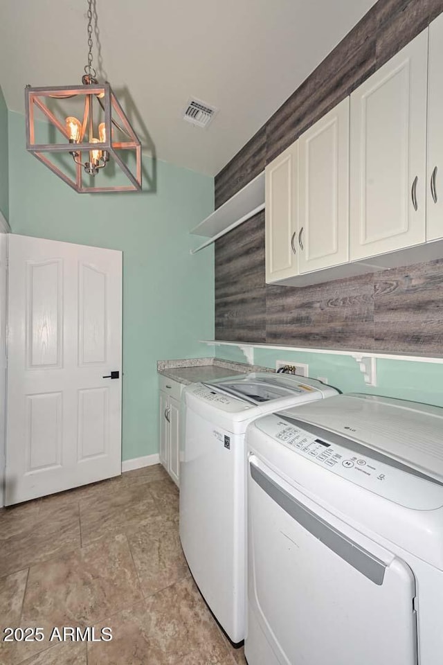 laundry room featuring an inviting chandelier, cabinets, and washer and dryer