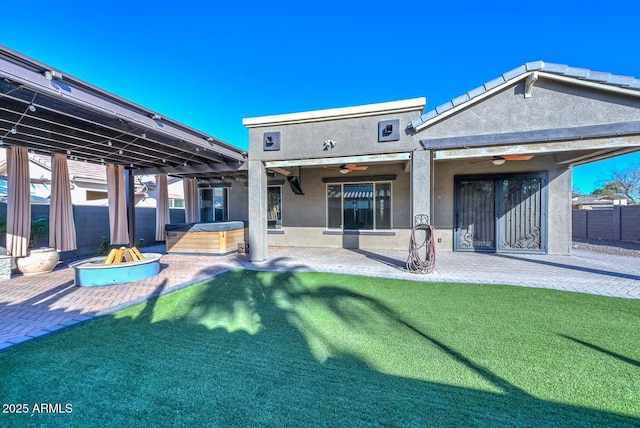 back of property with a hot tub, a patio, a yard, and ceiling fan