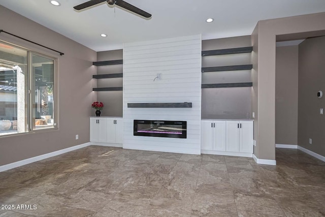 unfurnished living room featuring ceiling fan and a large fireplace