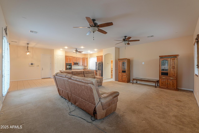 living room with light carpet, baseboards, visible vents, and arched walkways