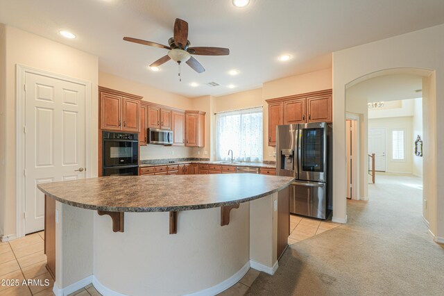 kitchen with light carpet, stainless steel appliances, a kitchen bar, and a center island