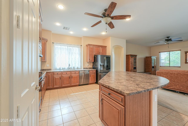 kitchen with light tile patterned floors, stainless steel appliances, a kitchen island, visible vents, and open floor plan