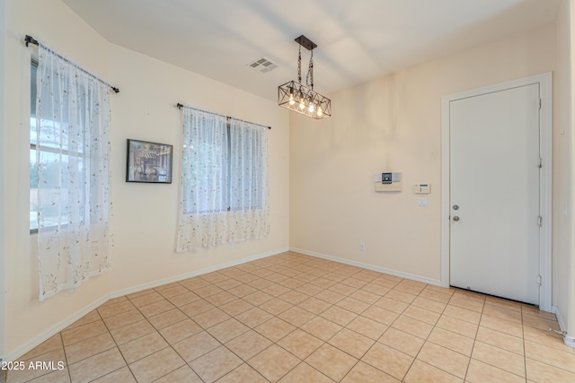 spare room with light tile patterned floors, plenty of natural light, visible vents, and baseboards