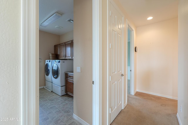 hall with visible vents, light carpet, baseboards, and separate washer and dryer