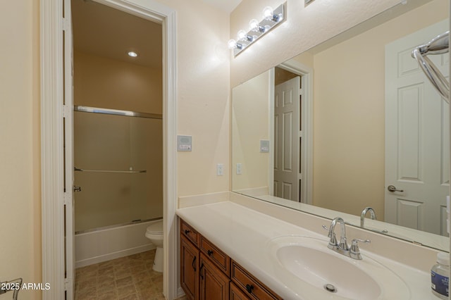 bathroom with combined bath / shower with glass door, vanity, and toilet