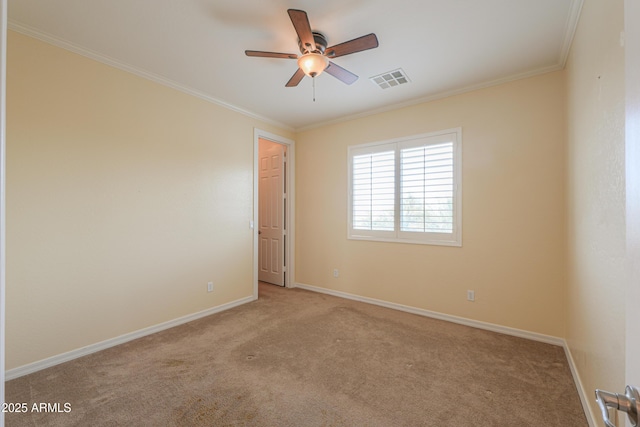 carpeted empty room featuring baseboards, ceiling fan, visible vents, and crown molding