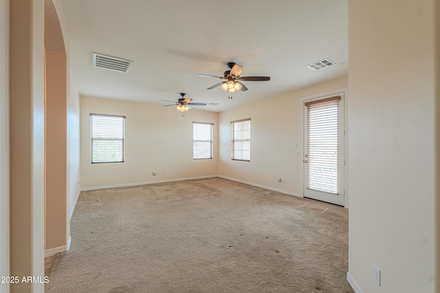 carpeted spare room featuring visible vents, ceiling fan, and baseboards