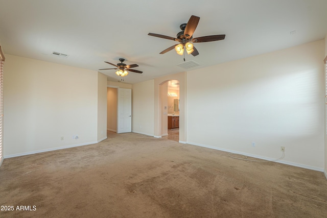 spare room with arched walkways, light carpet, visible vents, and baseboards