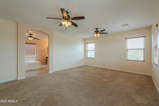 unfurnished bedroom with arched walkways, baseboards, visible vents, and light colored carpet