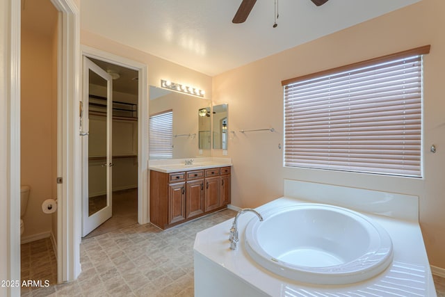 bathroom with a garden tub, toilet, a ceiling fan, vanity, and tile patterned floors