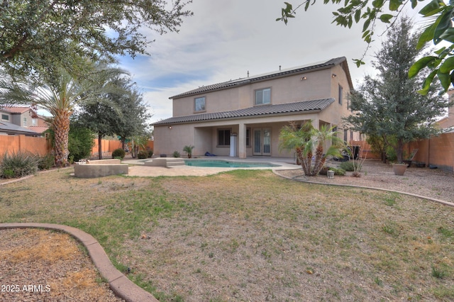 back of house featuring a patio, a fenced backyard, a tile roof, a lawn, and stucco siding