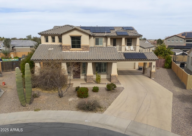 view of front facade featuring a tile roof, stucco siding, concrete driveway, fence, and stone siding