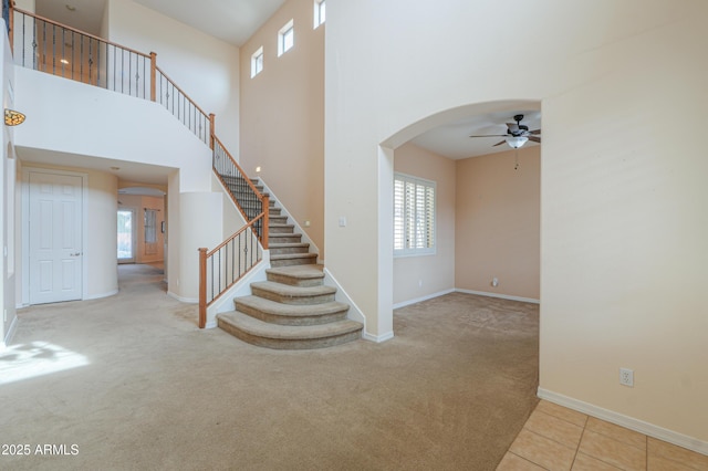 staircase with a towering ceiling, carpet, arched walkways, and baseboards