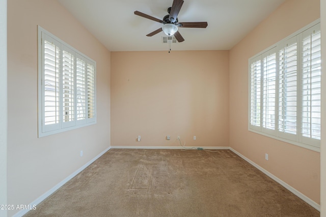 carpeted empty room with ceiling fan, visible vents, and baseboards