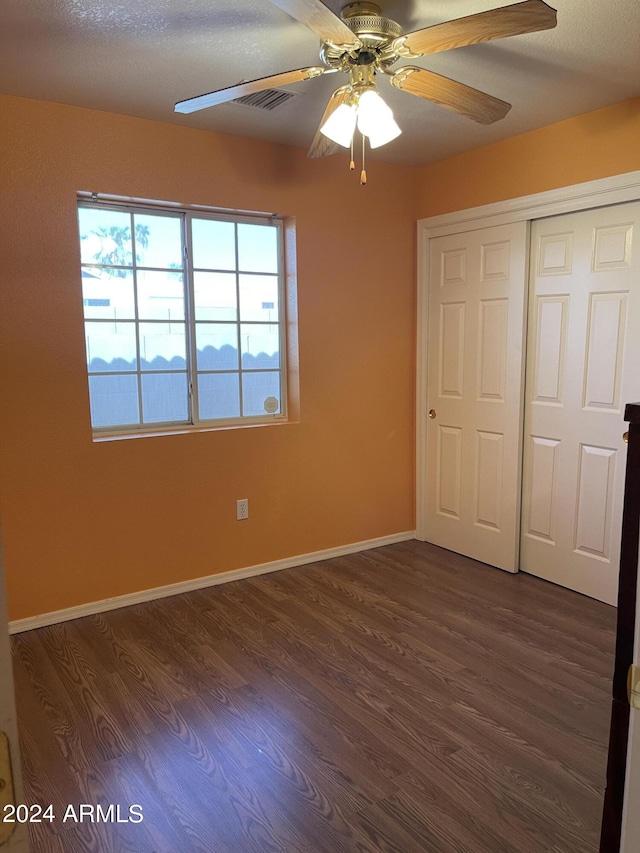 unfurnished bedroom featuring dark wood-type flooring, a closet, ceiling fan, and a textured ceiling