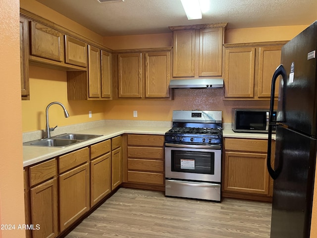 kitchen with a textured ceiling, appliances with stainless steel finishes, light wood-type flooring, and sink