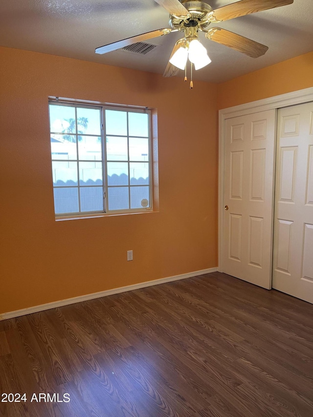 unfurnished bedroom featuring a closet, ceiling fan, a textured ceiling, and dark hardwood / wood-style flooring