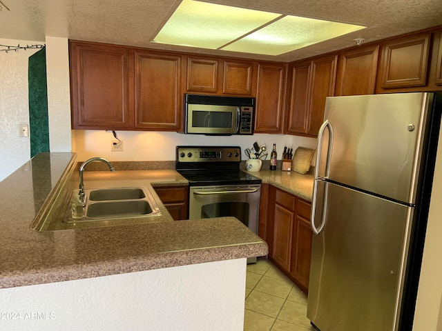 kitchen featuring stainless steel appliances, a textured ceiling, light tile patterned floors, sink, and kitchen peninsula