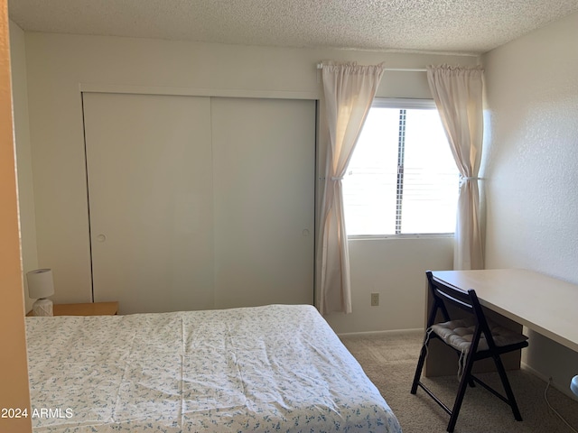 carpeted bedroom featuring a closet, multiple windows, and a textured ceiling