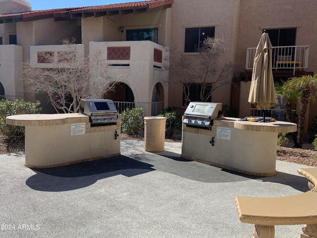 view of patio featuring area for grilling, a balcony, and exterior kitchen