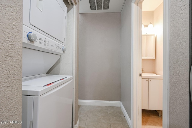 2301 E University Dr Unit 210, Mesa, AZ 85213 - laundry room featuring stacked washer and clothes dryer, light tile patterned floors, and a textured wall