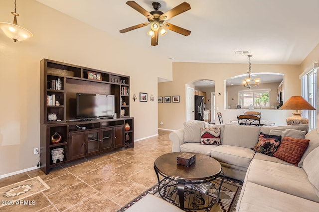 living area featuring arched walkways, baseboards, visible vents, and ceiling fan with notable chandelier