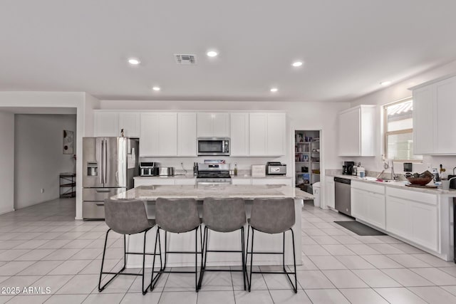 2347 W Sunland Ave, Phoenix, AZ 85041 - kitchen featuring stainless steel appliances, a kitchen island, a kitchen bar, white cabinetry, and recessed lighting
