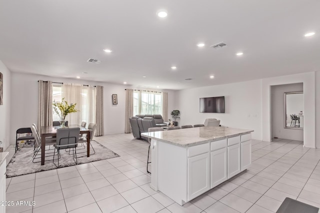 2347 W Sunland Ave, Phoenix, AZ 85041 - kitchen with a center island, white cabinets, recessed lighting, open floor plan, and light stone counters