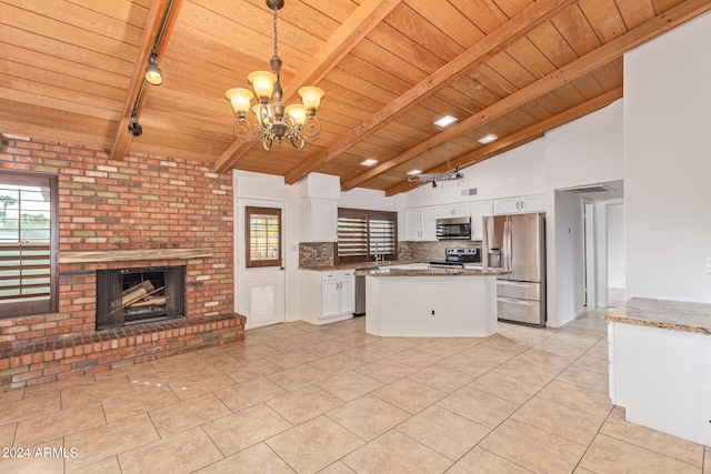 kitchen featuring white cabinetry, a fireplace, an inviting chandelier, appliances with stainless steel finishes, and decorative light fixtures