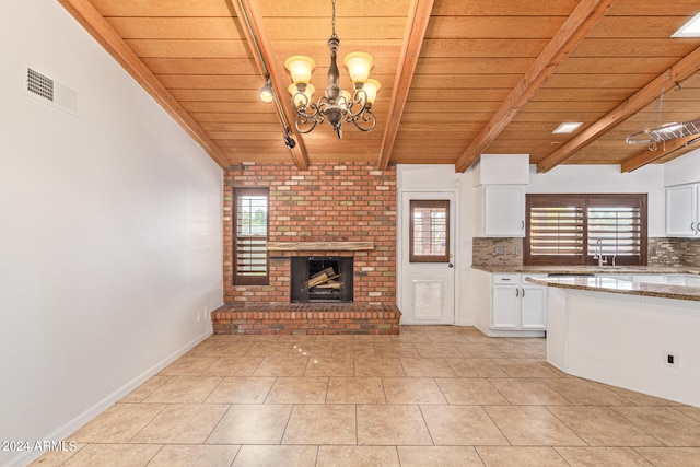 unfurnished living room with wood ceiling, a chandelier, sink, a brick fireplace, and light tile patterned floors