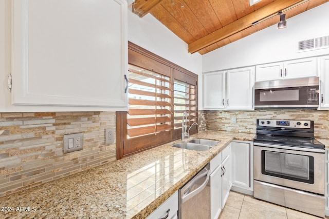 kitchen with vaulted ceiling with beams, appliances with stainless steel finishes, backsplash, and white cabinetry