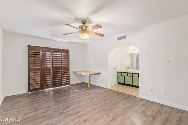 unfurnished bedroom with ceiling fan, light wood-type flooring, and sink