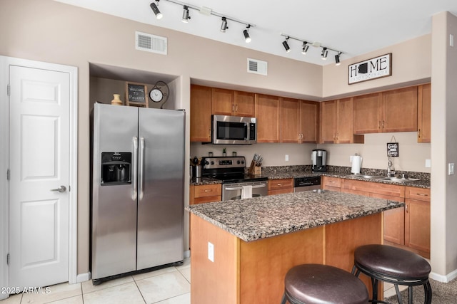 1920 E Bell Rd Unit 1189, Phoenix, AZ 85022 - kitchen with stainless steel appliances, brown cabinets, a kitchen island, a sink, and a kitchen bar