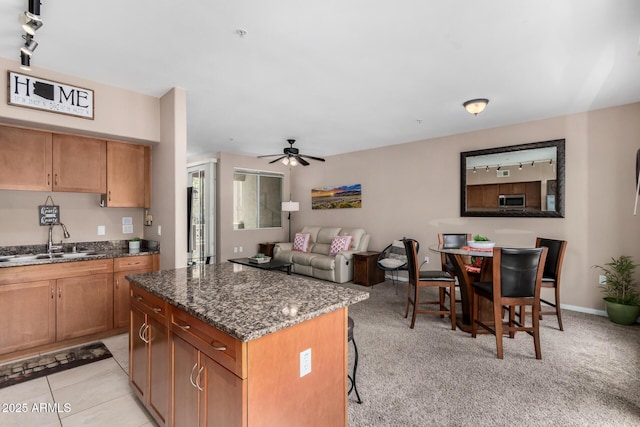 1920 E Bell Rd Unit 1189, Phoenix, AZ 85022 - kitchen with a sink, dark stone countertops, stainless steel microwave, a ceiling fan, and a center island