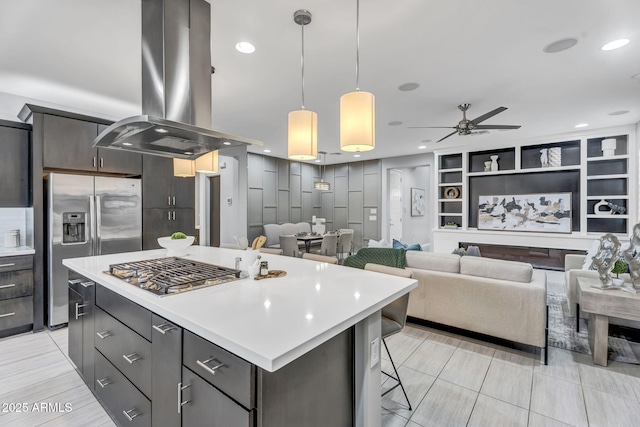 kitchen with a breakfast bar, a kitchen island, light countertops, appliances with stainless steel finishes, and island exhaust hood